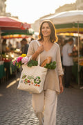 Lifestyle Prompt:** A sophisticated woman dressed in neutral linen clothing carries the 'Organik Nature' organic canvas tote bag, filled with fresh artisanal bread, organic greens, and flowers. She is smiling while walking through a sunlit, bustling European outdoor farmers' market. The lighting is warm and natural. Photorealistic style.
