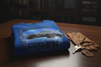Dramatic Ad Prompt: A close-up, cinematic shot of the crewneck folded neatly on a polished dark wood surface next to a pair of leather driving gloves and vintage car keys. The lighting is moody and dramatic, emphasizing the high-quality print of the sports car graphic and the thick weave of the premium fabric. 

