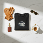  An elegant Instagram flat lay on a polished marble surface. The "Timeless Allegiance" tee is neatly folded, surrounded by curated accessories: a pair of vintage leather driving gloves, retro tortoiseshell sunglasses, a classic car key with a leather fob, and an artisan espresso cup. Natural, soft daylight.. 
