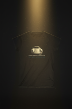 A high-contrast, cinematic studio shot of the "Timeless Allegiance" tee suspended against a dark, moody background. A beam of golden light highlights the central vintage sports car graphic, making the colors pop. Subtle smoke or dust motes dance in the light ray, emphasizing the "classic" theme. The fabric texture looks exceptionally soft and premium. 